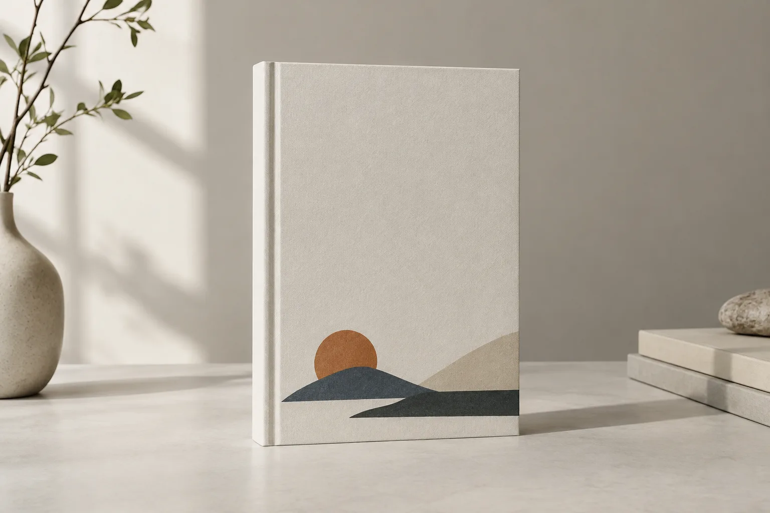 Un livre à couverture vierge posé debout, avec un petit motif géométrique placé en bas et une large zone libre au-dessus.